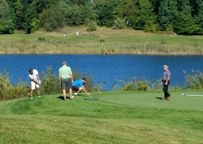four men golfing by water