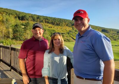 two men and a woman posing for a photo at a golf course