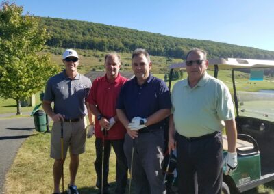 four men holding golf clubs on a sunny day