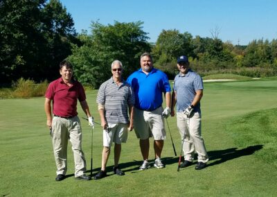 four men posing for a photo on a golf course