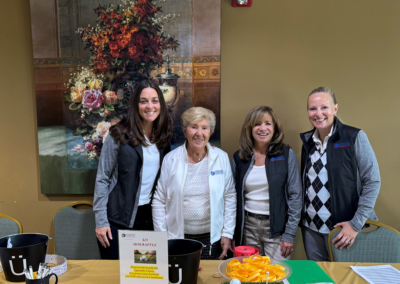 four women at a raffle table, posing for a photo