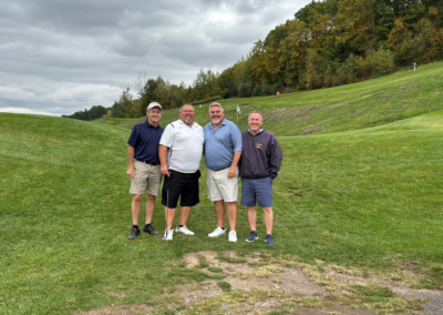 four men posing for a photo on a golf course